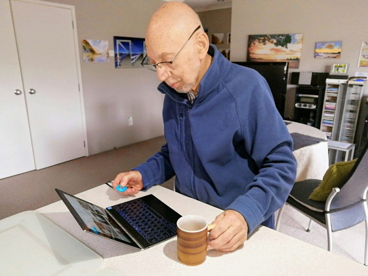 elderly man holding a cup and watching instruction on laptop